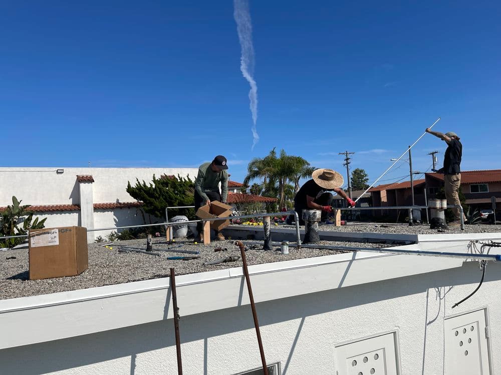 Workers performing maintenance on a commercial rooftop on a sunny day.