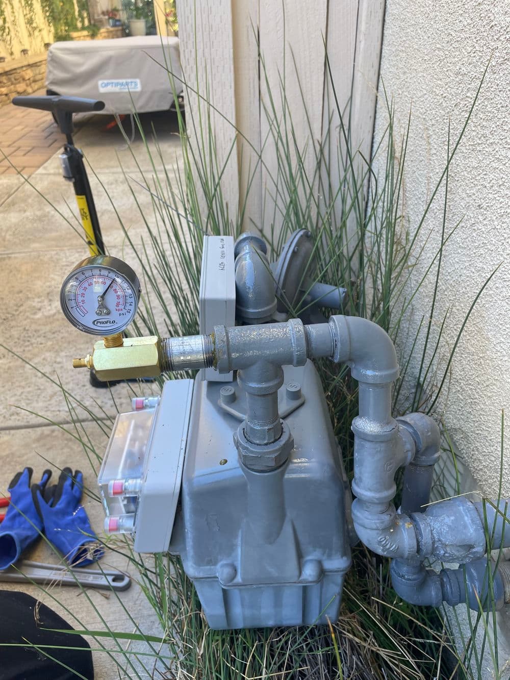 Gas pressure regulator installed outside, featuring a pressure gauge and connected pipes.