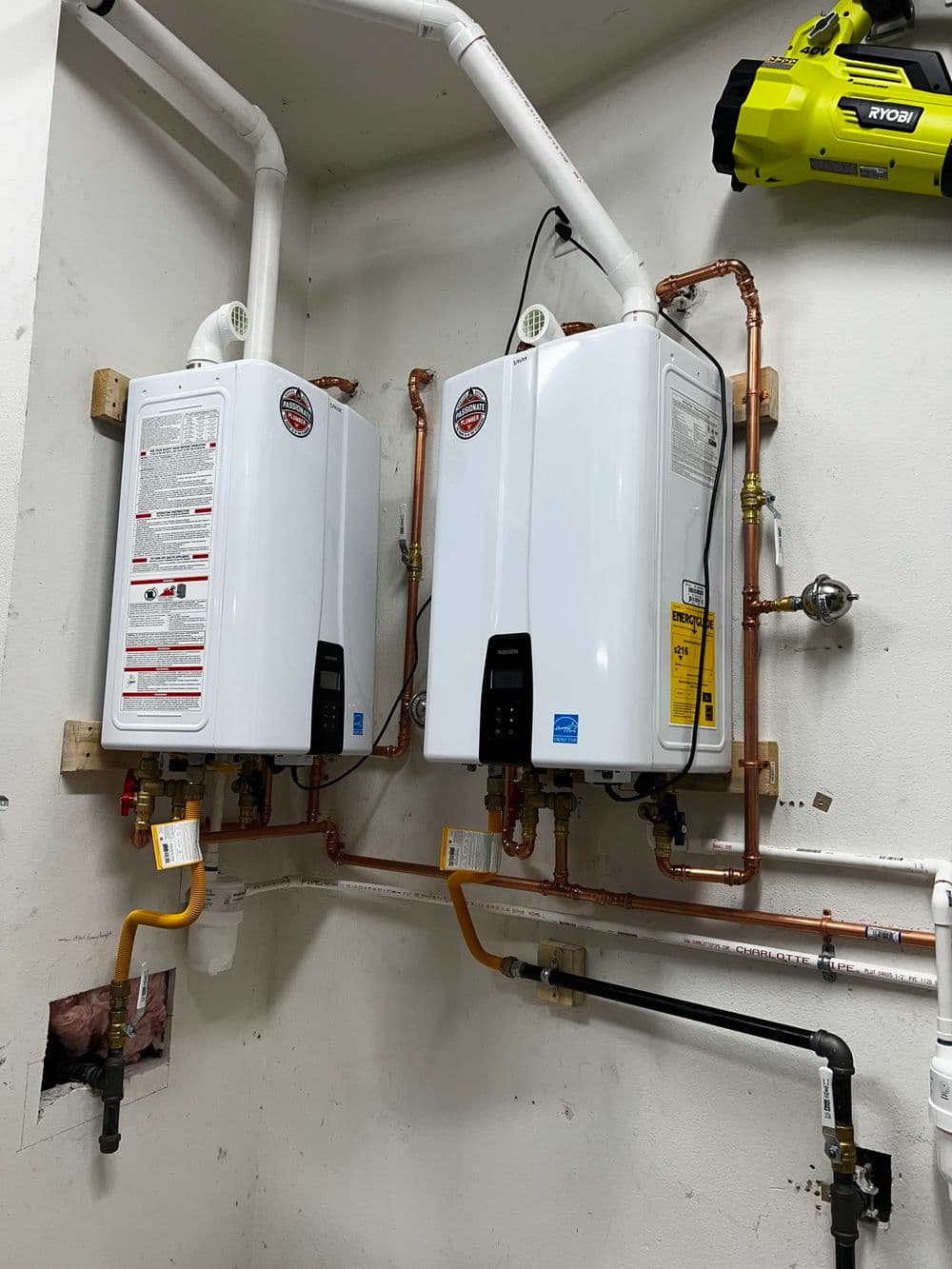 Tankless water heaters installed on a wall, featuring copper piping and valves.