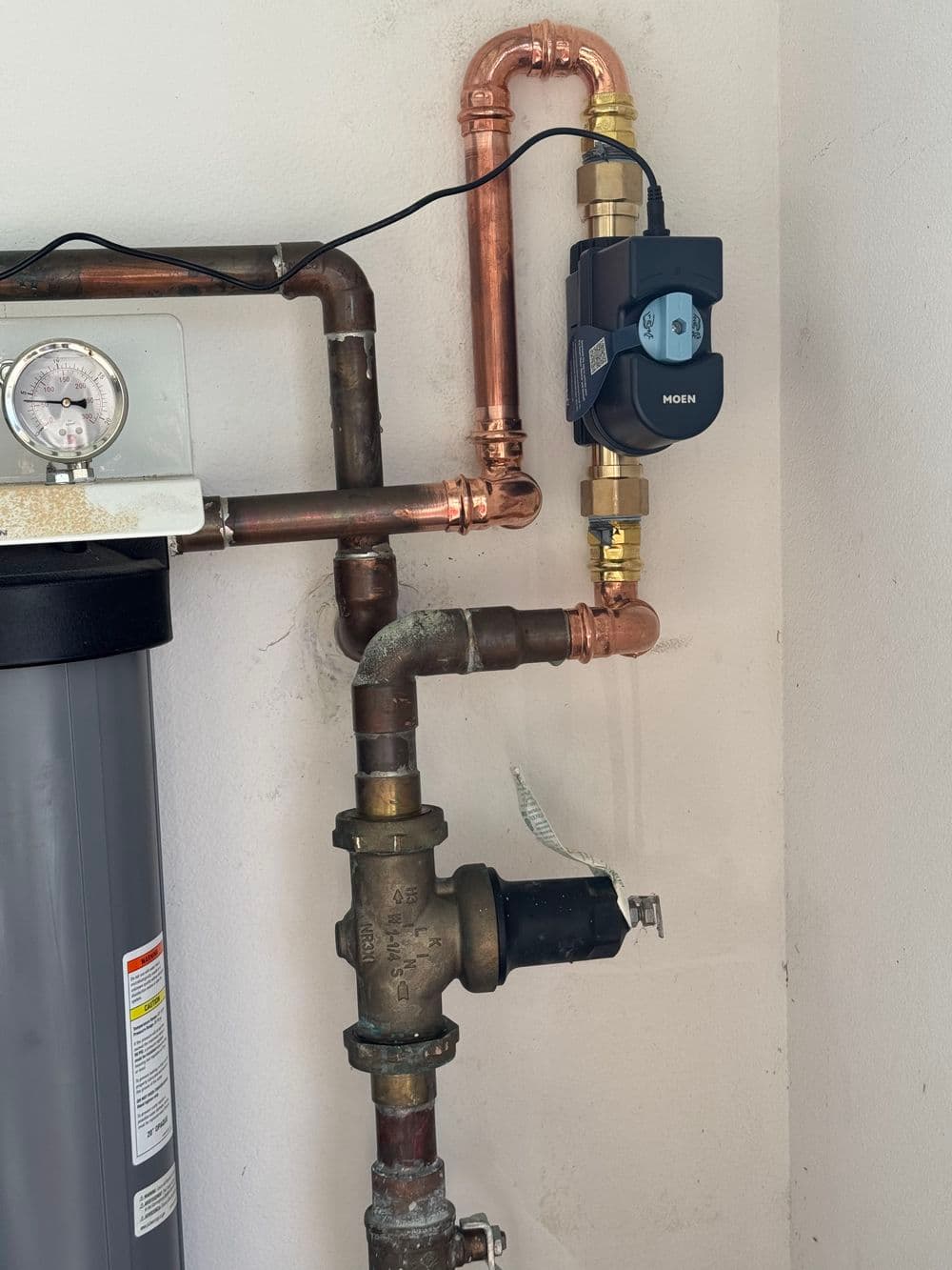 Copper plumbing with flow meter and pressure gauge, installed on a water filtration system.