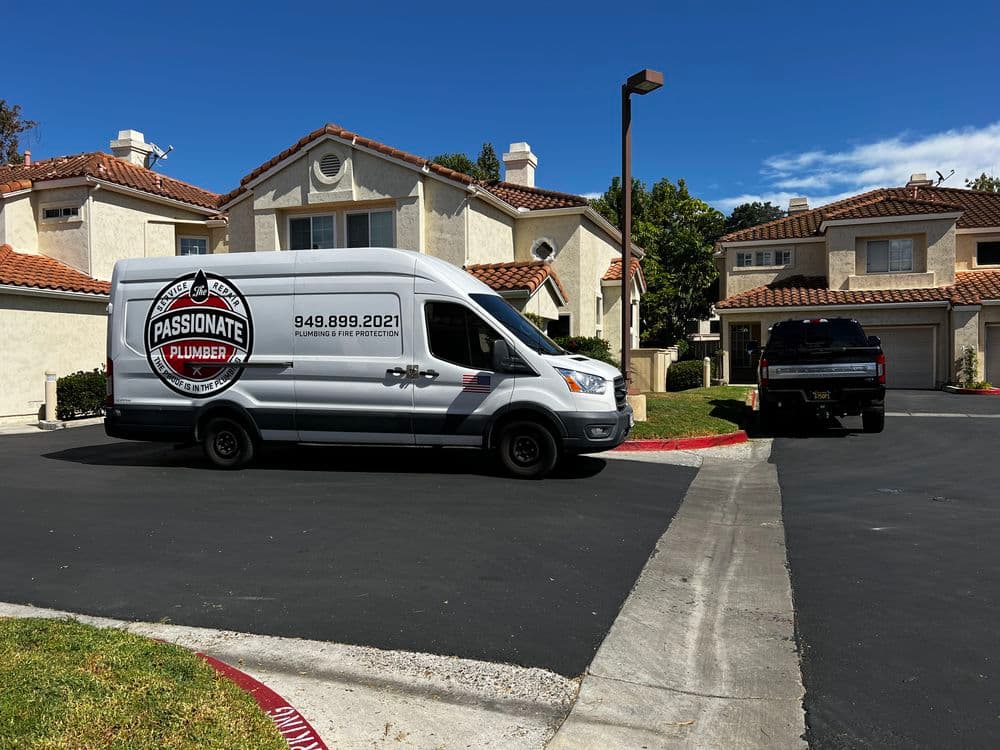 Passionate Plumber van parked outside suburban homes with clear blue sky.