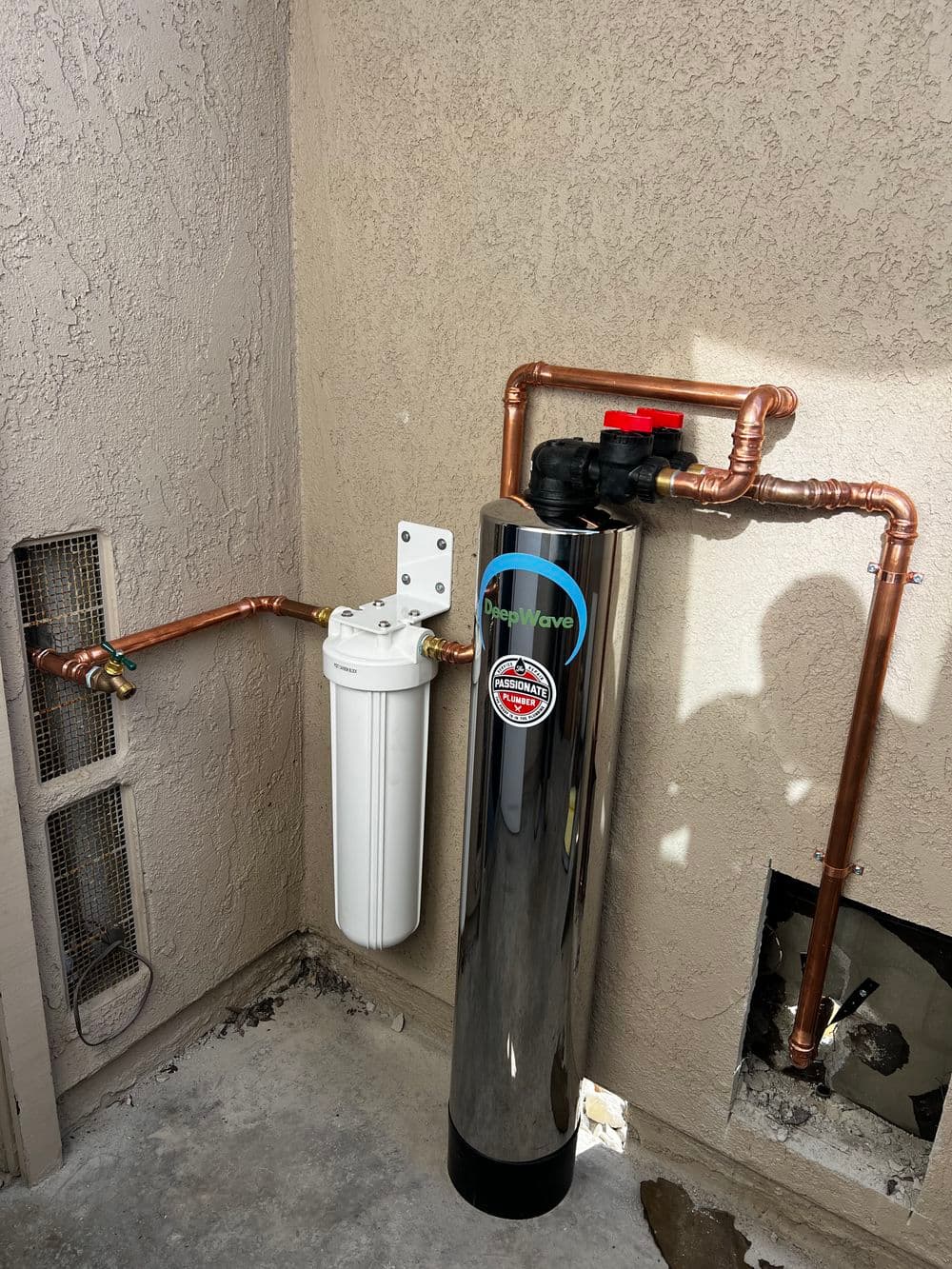 Water filtration system featuring a white filter and shiny black tank with copper pipes installed.