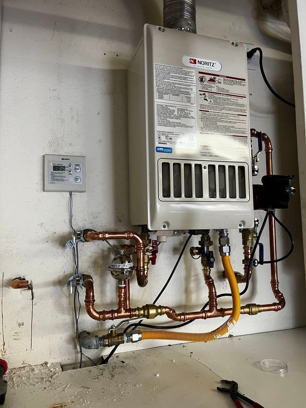 Noritz tankless water heater installation with copper and yellow gas piping.