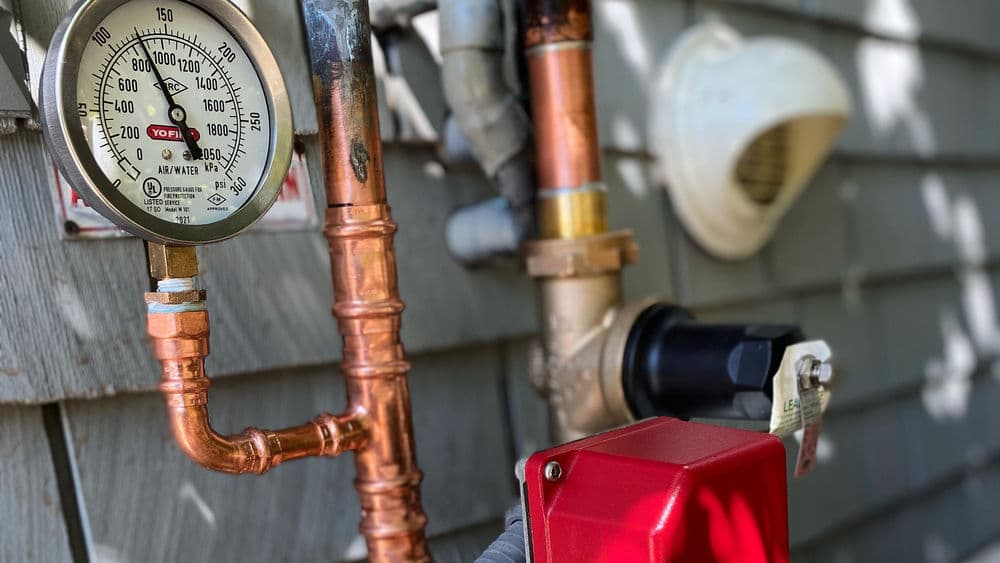 Pressure gauge and water meter on a house exterior showcasing plumbing details.
